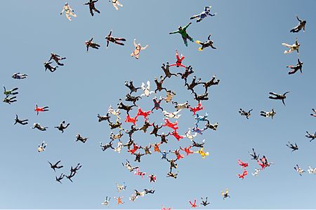 Photo of several skydivers in a formation, depicting the ease at which an object passes through a non-condensed state.
